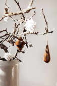 Branches in a vase with paper ornaments hanging from them