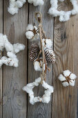 Garland with star of cotton and whitewashed cones on wooden background