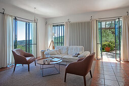 Ledersessel und Sofa in mediterranem Wohnzimmer mit Terrakottafliesenboden
