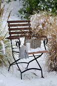 A basket of larch branches on a snow-covered garden chair