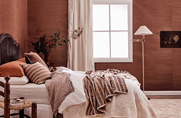 Doppelbett mit antikem, französischem Betthaupt, Kissen und Decken in Erdtönen