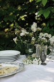 Festively laid table with white tablecloth and spiraea