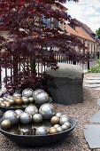 Bowls with silver balls, Japanese maple, and granite block shaped boulder along the garden path