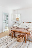 Doppelbett mit Vintage-Leinenbettwäsche im Schlafzimmer mit Blick ins Badezimmer
