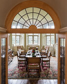 View through open double doors into dining room with antique chairs