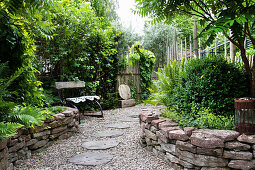 Dry stone wall and lush planting along garden path, seating in background