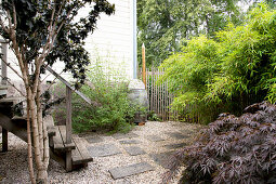 Garden with gravel and concrete slabs and wooden steps