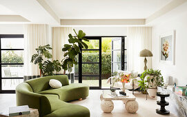 Organisch geformte Couch mit grünem Bezug und Vintage Marmortisch in hellem Wohnraum