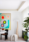 Designer floor lamp and sculpture in a dining area, modern art on wall