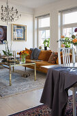 Braun-orangefarbenes Plüschsofa mit Kissen und Couchtisch mit Glasplatte in hellem Wohnzimmer