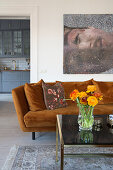 Braun-orangefarbenes Plüschsofa mit Kissen und Couchtisch mit Glasplatte in hellem Wohnzimmer