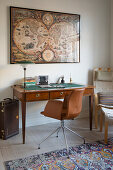 Antiker Schreibtisch mit braunem Lederstuhl und große gerahmte Weltkarte an der Wand