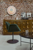 Coffee table, upholstered chair, and vintage sideboard in front of a brick wall