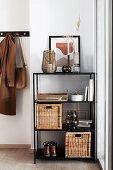 Black shelf with rattan objects in the hallway