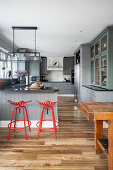 Offene Küche mit grauen Schrankfronten und roten Barhockern