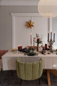 Festlich gedeckter Weihnachtstisch mit Kerzen, Polsterstühle mit Samtbezug um den Tisch