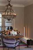Festive Christmas table with candles, chandelier above, purple velvet chair