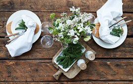 Place setting and table arrangement in green and white on rustic wooden table