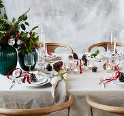 Christmas table set with bouquets of flowers, pine cones and lanterns