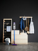 Utensils for spring cleaning, sideboard and clothes horse in room with black wall