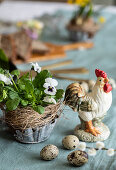 Easter decoration with pansies, rooster figure, and quail eggs
