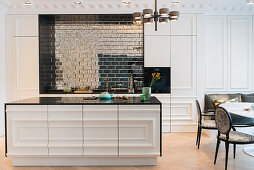 White kitchen island black top and antique looking mirror tiles in open-plan kitchen