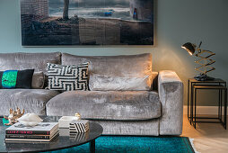 Black coffee table and velvet sofa, above large-format photograph on the wall in the living room
