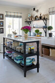Black kitchen island workbench with marble top and crockery in the kitchen