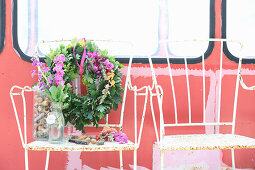 Eichenlaubkranz mit bunten Blüten auf altem Metallstuhl