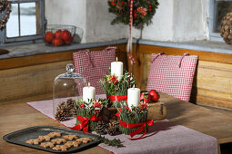 Winterliche Kerzendekoration mit roten Schleifen und Tannenzapfen auf Holztisch
