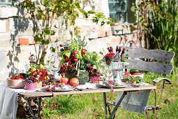 Gedeckter Sommertisch, dekoriert mit Früchten, Beeren und Gemüse