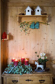 Advent wreath made of natural materials with red candles on a wooden chest of drawers
