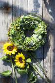 Wreath of green hydrangeas and poppy capsules next to sunflowers