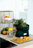 Wire basket, citrus press and bag of artichokes on kitchen worktop