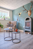 Side tables, a cosy armchair and a fireplace with antlers above it in a living room