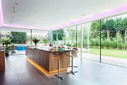 An elegant kitchen island with indirect lighting in the living room with all-round glazing