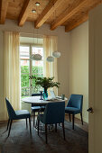 Blaue Lederstühle um runden Tisch im Zimmer mit Holzbalkendecke