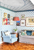 Cushion sofa and armchair in the room, wallpaper with geometric pattern, and picture gallery on the wall