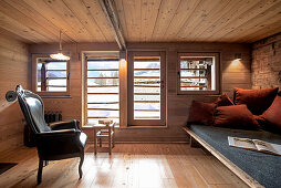 Sofa with cushions and leather armchair in a wooden hut