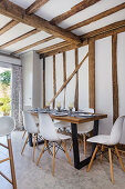 Essbereich mit Klassikerstühlen in offener Küche mit Holzbalkendecke