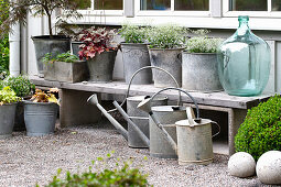 Zinc pots, balloon bottle and watering cans on house wall
