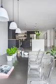 Essbereich mit transparenten Stühlen, im Hintergrund Küche in offenem Wohnraum