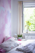 Bett im Schlafzimmer mit individueller Wandgestaltung in rosa Tönen