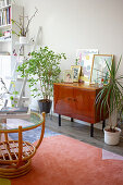 60er Jahre Sideboard mit Bildern, Zimmerpflanzen und Rattan-Couchtisch mit Glasplatte im Wohnzimmer