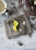 Horned violet, feather, and cutlery on knitted napkin