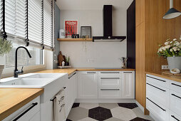 Modern white kitchen with wooden elements, hexagonal tiled floor