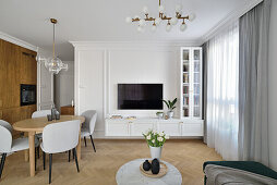 Round table with chairs in front of white living room wall with TV set