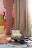 Low table and leather armchair in front of floor-length curtain and tapestry