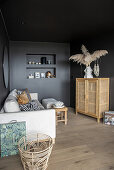 Helles Sofa mit Kissen und Highboard im Wohnzimmer mit schwarzen Wänden