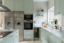 Küche in Mintgrün mit Marmorarbeitsplatte und Sidebyside-Kühlschrank